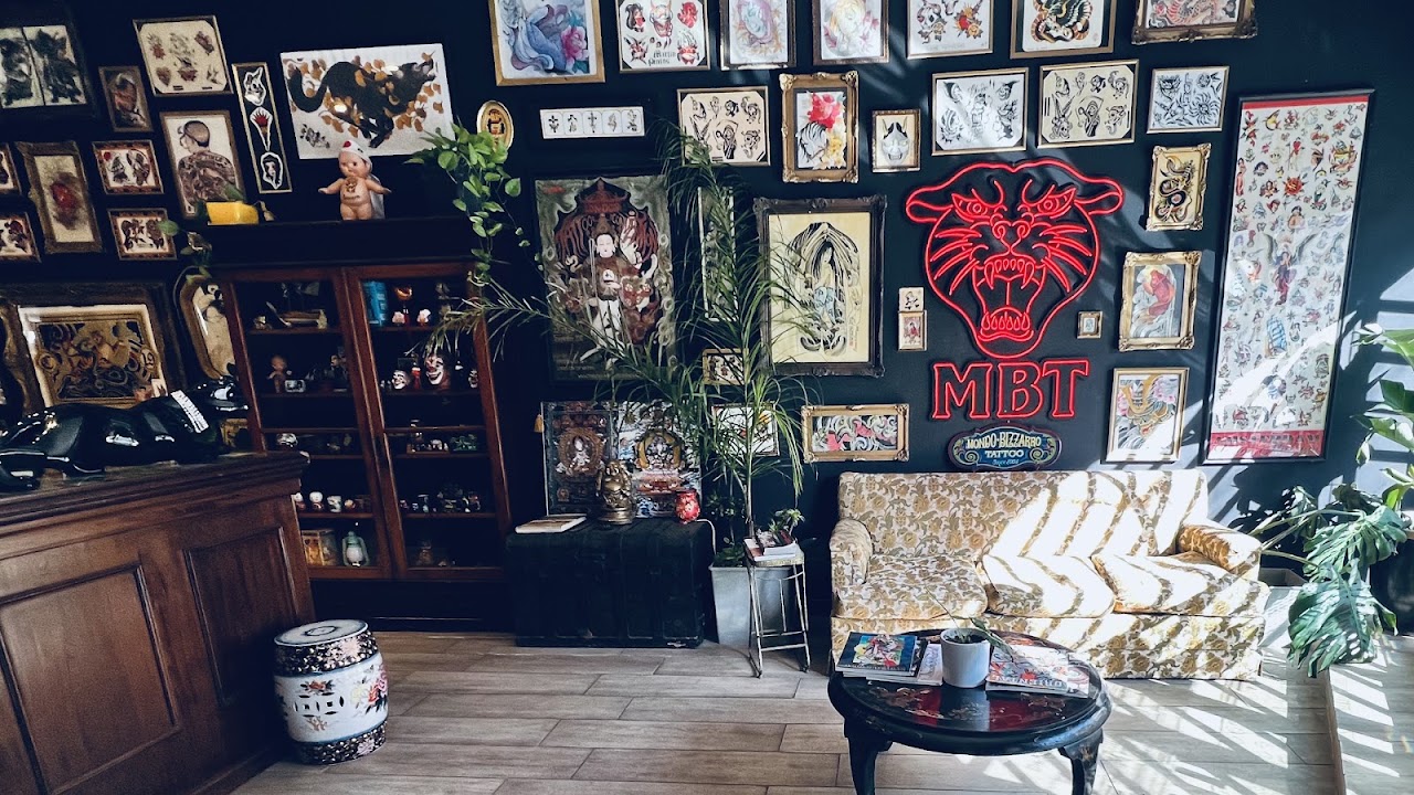 Sala de espera de Mondo Bizarro Tattoo con sillón vintage y pared de flash art